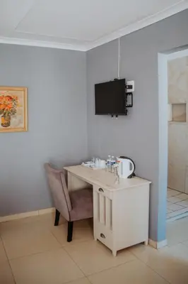 a desk with a chair and a tv on a wall at Karabelo guesthouse in Groblersdal