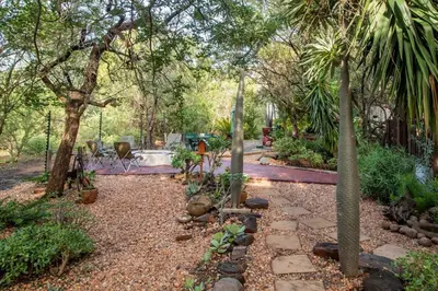 a garden with trees and a stone pathway at Woodlandsbushlodge in Hoedspruit