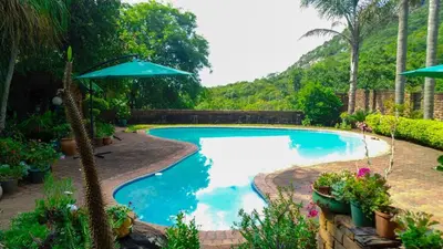 a swimming pool with an umbrella in a yard at Kneizenberg Boutique Lodge & Spa in Louis Trichardt