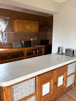 a kitchen with wooden cabinets and a white counter top at The Gem Emerald in Graskop