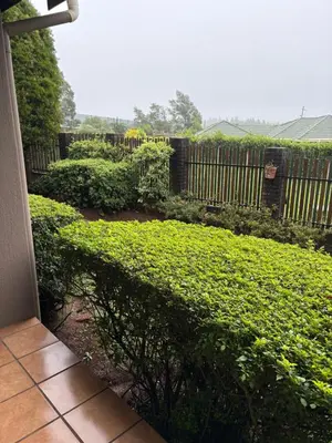a garden with green bushes and a wooden fence at The Gem Emerald in Graskop
