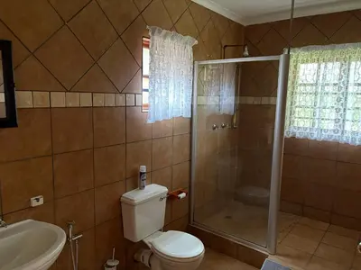 a bathroom with a shower and a toilet and a sink at The Gem Emerald in Graskop