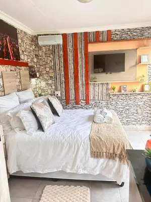 a bedroom with a white bed with a stone wall at MRH Self Check- In Express Homestay in Modimolle