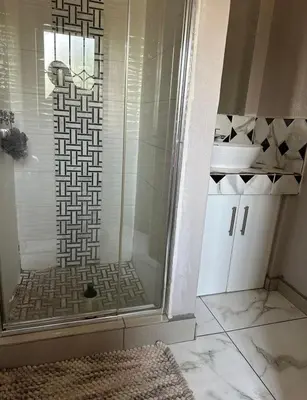 a bathroom with a glass shower with a sink at Riverside Gardens 2 bedroom Home in Nelspruit
