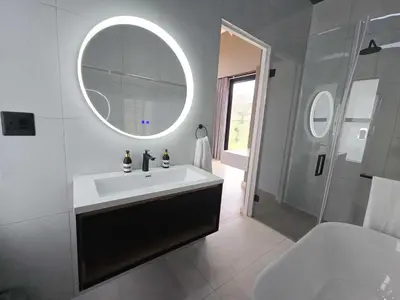 a white bathroom with a sink and a mirror at The Curve in Dullstroom