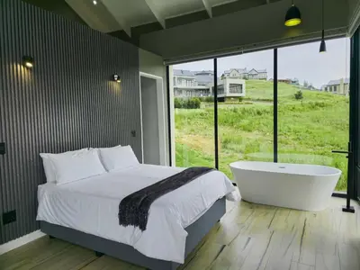 a bedroom with a bed and a bath tub and a window at The Curve in Dullstroom