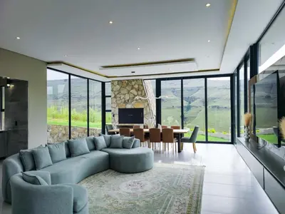 a living room with a blue couch and a dining room at The Curve in Dullstroom