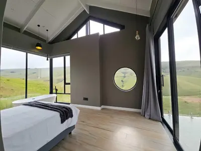 a bedroom with a large bed and large windows at The Curve in Dullstroom