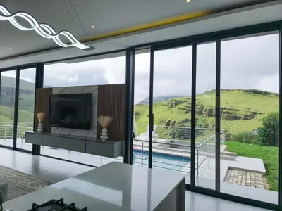 a living room with a tv and large glass windows at The Curve in Dullstroom