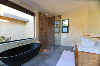 a bathroom with a black bath tub and a sink at Bush House Zandspruit in Hoedspruit
