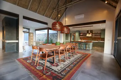 a kitchen and dining room with a wooden table and chairs at Bush House Zandspruit in Hoedspruit