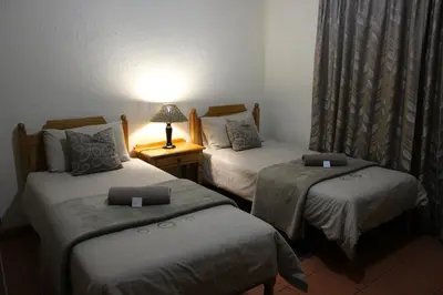 a room with two beds and a lamp on a table at Mogodi Lodge in Graskop