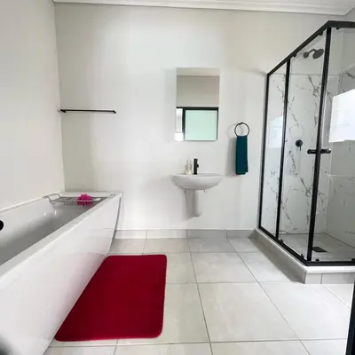 a bathroom with a tub and a sink and a red rug at UNIT 1487 The blyde crystal lagoon in Pretoria