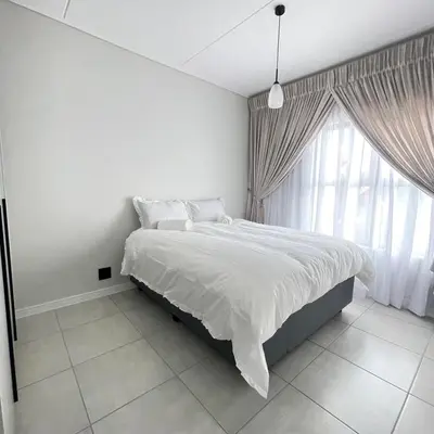a white bedroom with a bed and a large window at UNIT 1487 The blyde crystal lagoon in Pretoria