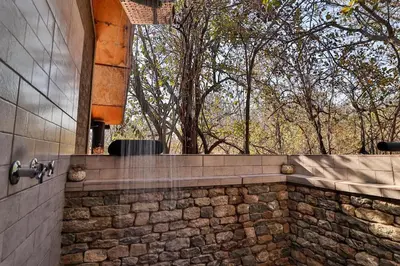 a bathroom with a stone wall with a window at Shiringa kruger lodge in Marloth Park