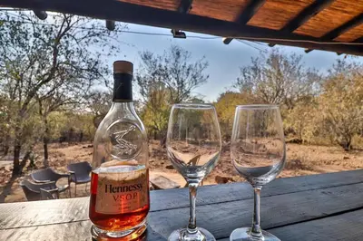 two wine glasses and a bottle on a wooden table at Shiringa kruger lodge in Marloth Park