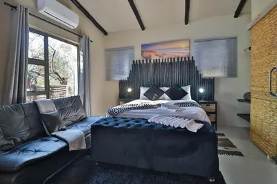 a bedroom with a large bed and a couch at Shiringa kruger lodge in Marloth Park