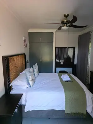 a bedroom with a large white bed with a fan at The Golden Eagle Guest House in Kempton Park