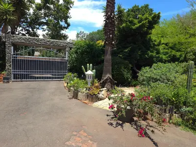 a driveway with a gate and a bunch of flowers at The Golden Eagle Guest House in Kempton Park
