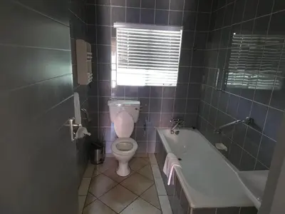a bathroom with a toilet and a bath tub at The Golden Eagle Guest House in Kempton Park