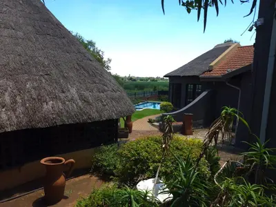 a house with a thatch roof and a playground at The Golden Eagle Guest House in Kempton Park