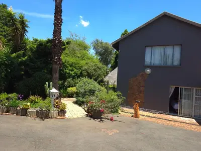 a black house with plants and a fire hydrant at The Golden Eagle Guest House in Kempton Park