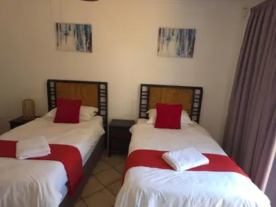 a bedroom with two beds with red and white pillows at The Golden Eagle Guest House in Kempton Park