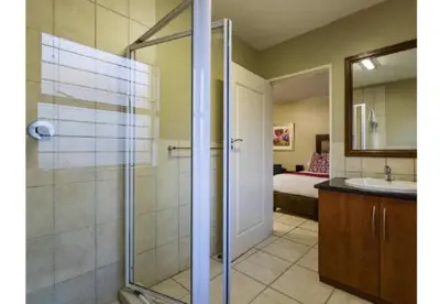 a bathroom with a shower and a sink and a bed at Cozy Apartment in Hatfield in Pretoria