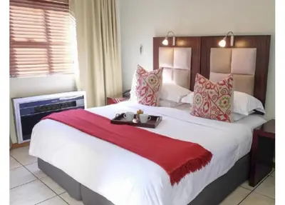 a bedroom with a large white bed with red pillows at Cozy Apartment in Hatfield in Pretoria