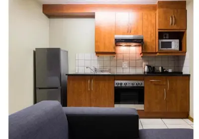 a kitchen with wooden cabinets and a stainless steel refrigerator at Cozy Apartment in Hatfield in Pretoria