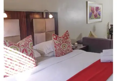 a bedroom with a bed with red and white pillows at Cozy Apartment in Hatfield in Pretoria