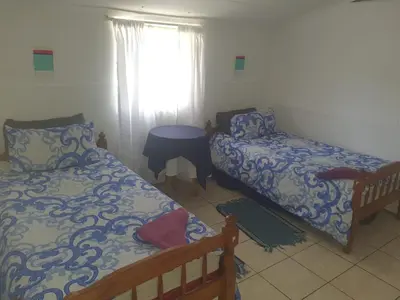 a bedroom with a bed and a desk and a window at Chalet 4 at Cynthias Country in Hartbeespoort
