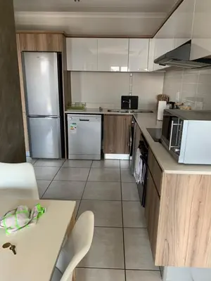 a kitchen with a refrigerator and a table in it at Sushii luxury apartment The Blyde in Pretoria