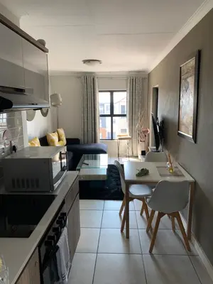 a kitchen and living room with a table and a couch at Sushii luxury apartment The Blyde in Pretoria