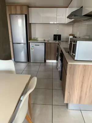 a kitchen with a refrigerator and a table and chairs at Sushii luxury apartment The Blyde in Pretoria