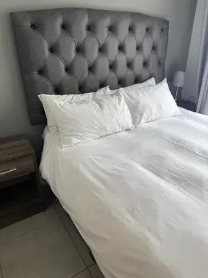 a white bed with a gray headboard and white pillows at Treger views in Midrand