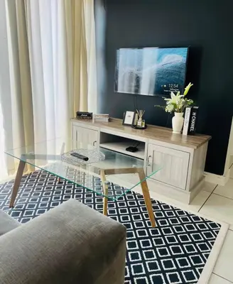 a living room with a glass table and a television at SoulSerene Inn in Pretoria
