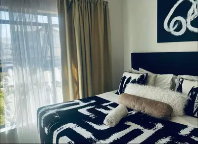 a bed with a blue and white blanket and a window at SoulSerene Inn in Pretoria