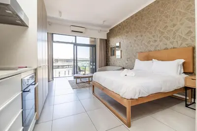 a bedroom with a large bed and a balcony at Urban Luxury at The Trilogy in Pretoria