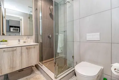 a bathroom with a shower and a toilet and a sink at Urban Luxury at The Trilogy in Pretoria