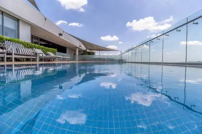 a swimming pool with chairs and a building at Urban Luxury at The Trilogy in Pretoria