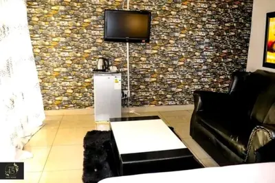 a living room with a couch and a tv on a wall at Leisure 45 Guest House in Kwaggafontein