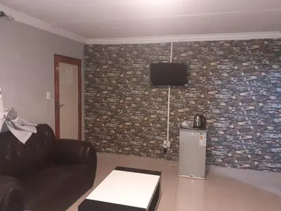 a living room with a couch and a tv on a brick wall at Leisure 45 Guest House in Kwaggafontein