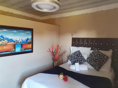 a bedroom with two beds and a painting on the wall at Leisure 45 Guest House in Kwaggafontein