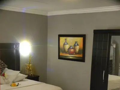a bedroom with a picture of vases on the wall at Leisure 45 Guest House in Kwaggafontein