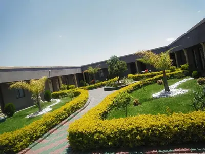 a building with a garden with yellow flowers and trees at Leisure 45 Guest House in Kwaggafontein