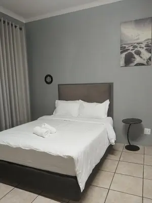 a bedroom with a white bed with a towel on it at Capital Park entire rental unit in Pretoria