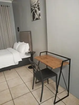 a room with a bed and a table and a chair at Capital Park entire rental unit in Pretoria
