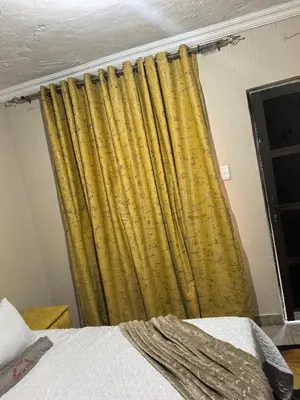 a yellow curtain in a room with a bed at samama guesthouse in Groblersdal