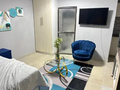 a bedroom with a bed and a blue chair and a tv at samama guesthouse in Groblersdal